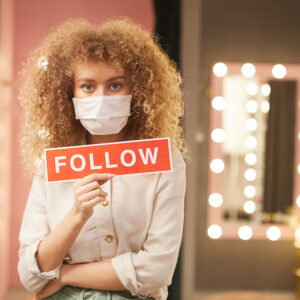 Woman Wearing Mask and Holding Follow Sign For Twitter Instagram and Social Media - - Training By The Digital Bakery Creative Agency in Dundalk Louth